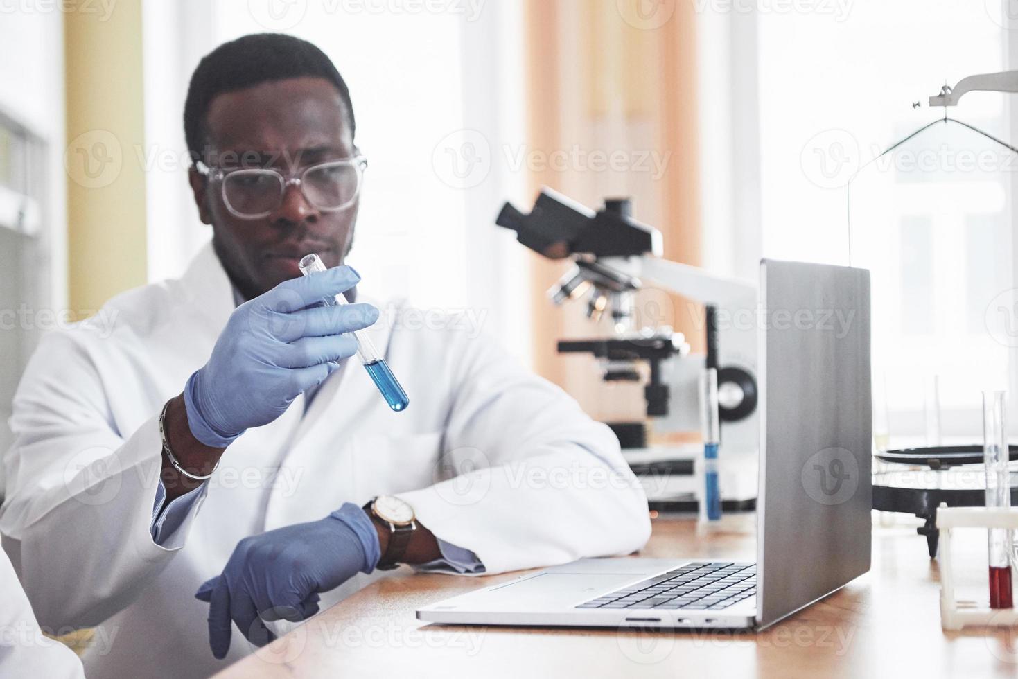 um trabalhador afro-americano trabalha em um laboratório conduzindo experimentos. foto