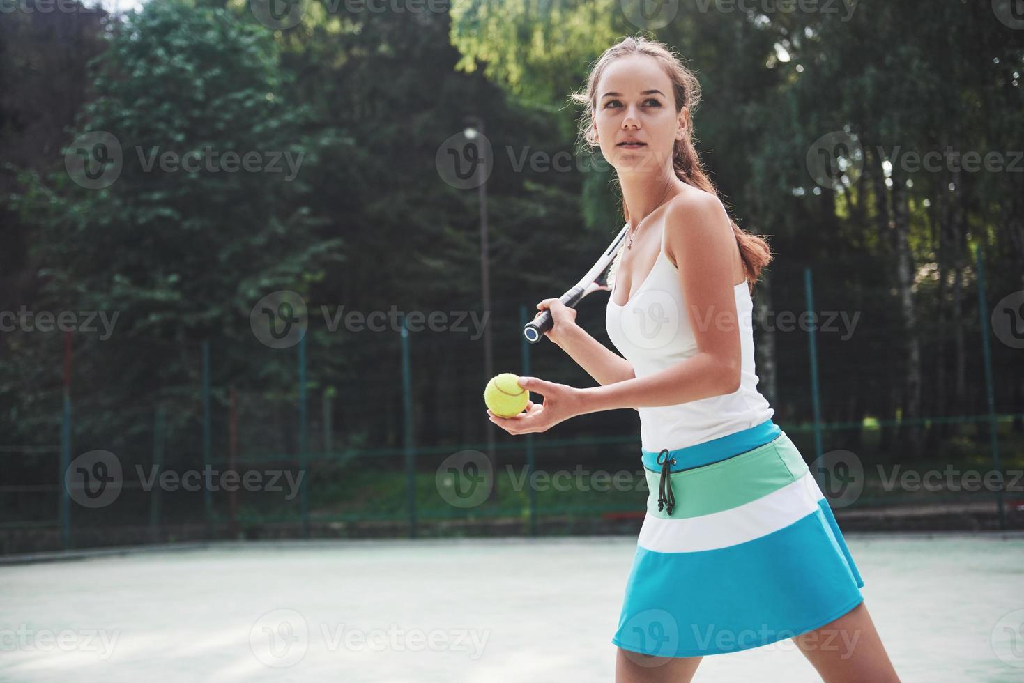 mulher em roupas esportivas serve bola de tênis. foto