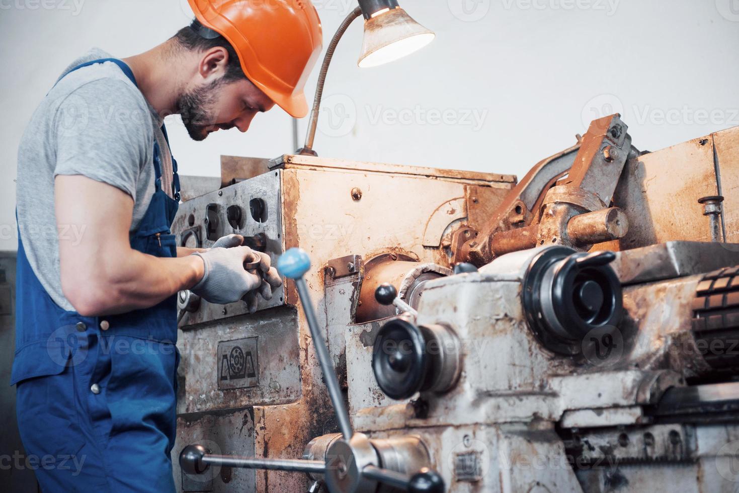 retrato de um jovem trabalhador em um capacete em uma grande usina de metais. o engenheiro atende as máquinas e fabrica peças para equipamentos de gás foto