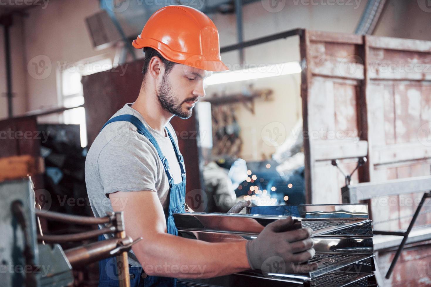 retrato de um jovem trabalhador em um capacete em uma grande usina de metais. o engenheiro atende as máquinas e fabrica peças para equipamentos de gás foto