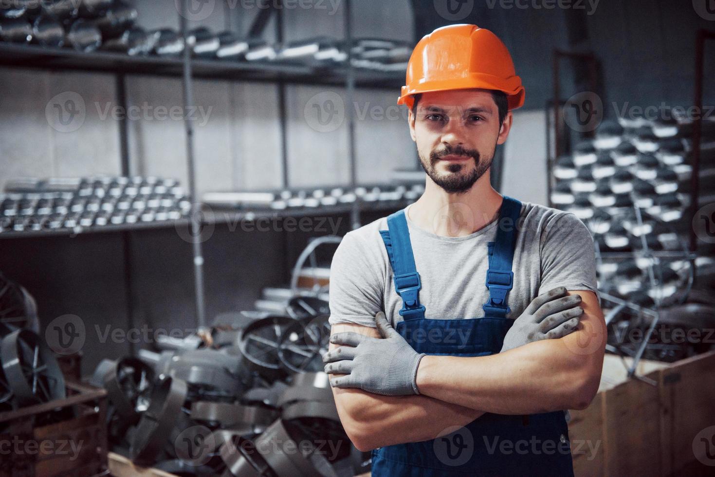 retrato de um jovem trabalhador em um capacete em uma grande usina de metais. shiftman no armazém de produtos acabados foto