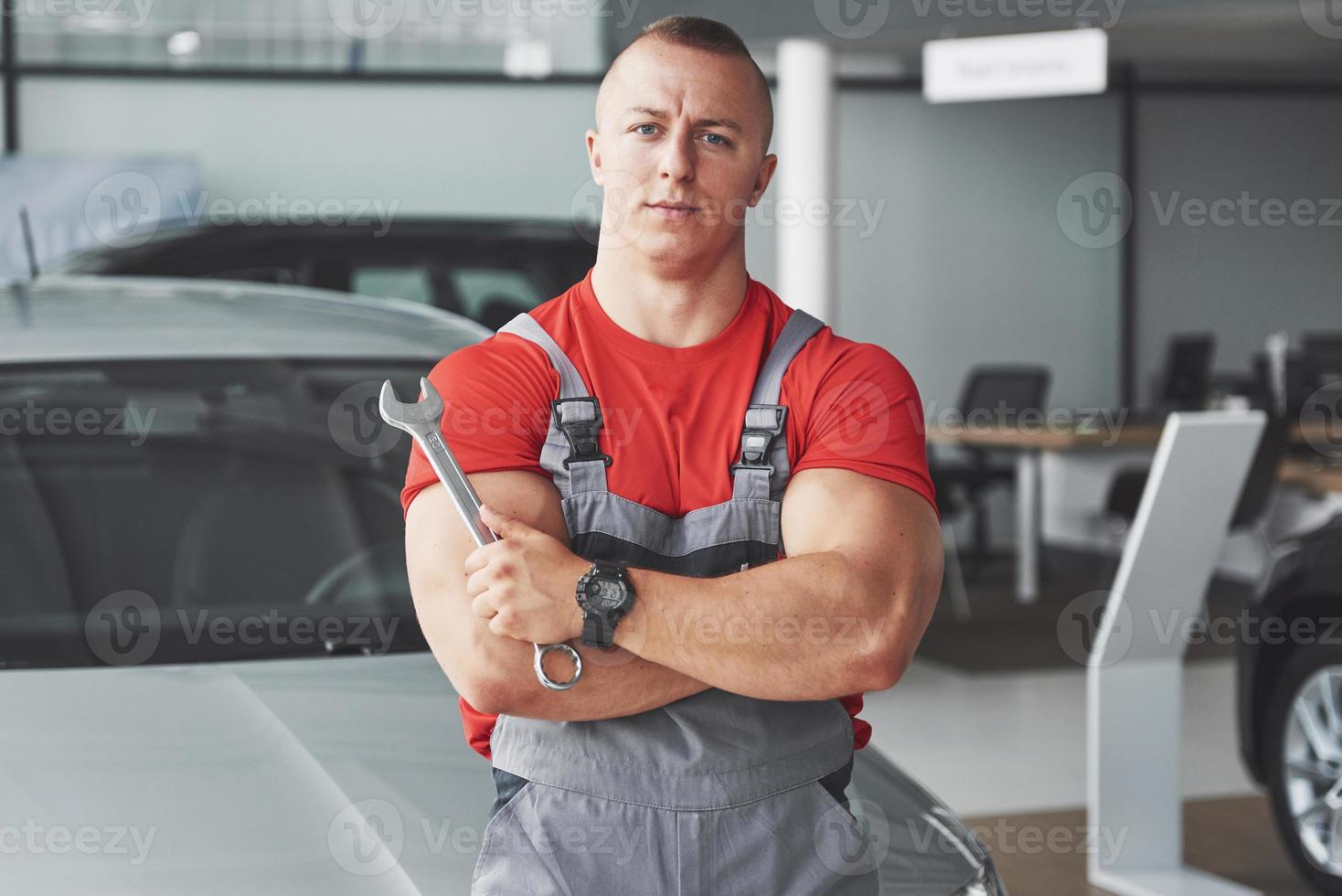 mãos do mecânico de automóveis com a chave inglesa na garagem foto