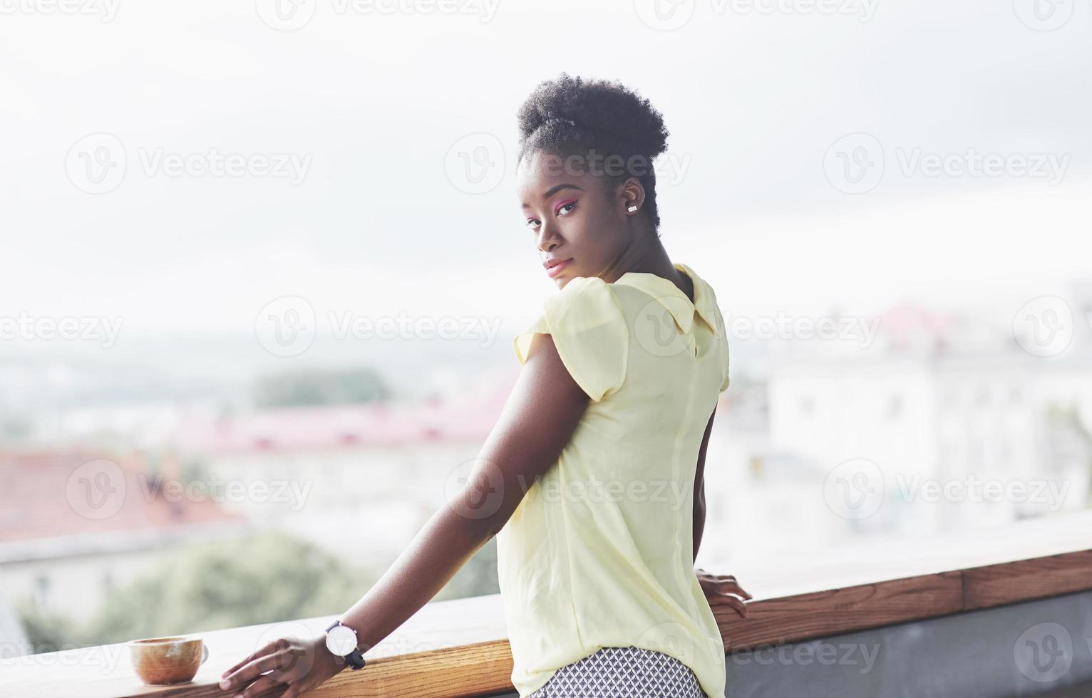 jovem garota afro-americana com cabelo escuro encaracolado pensativa em um café. lindo lugar aconchegante. foto