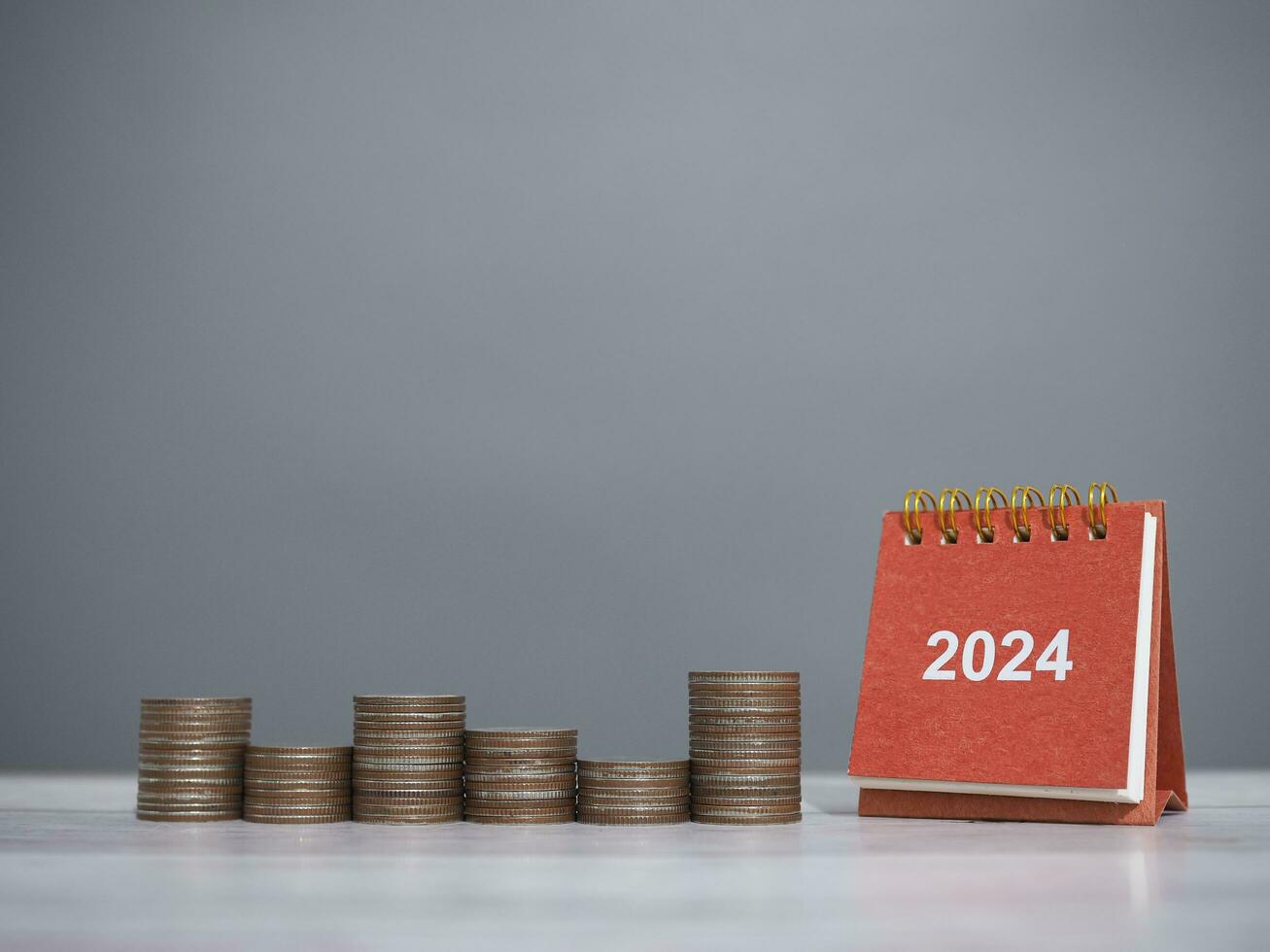 2024 escrivaninha calendário e pilha do moedas. a conceito do salvando dinheiro para financeiro, investimento e o negócio crescendo dentro Novo ano 2024. foto