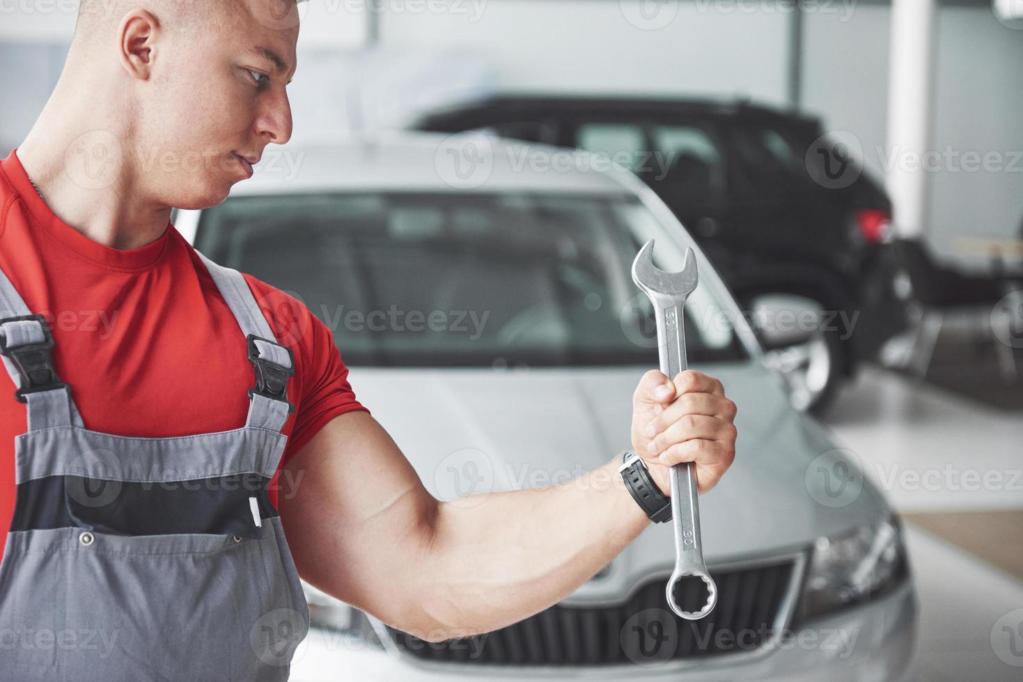 mãos do mecânico de automóveis com a chave inglesa na garagem foto