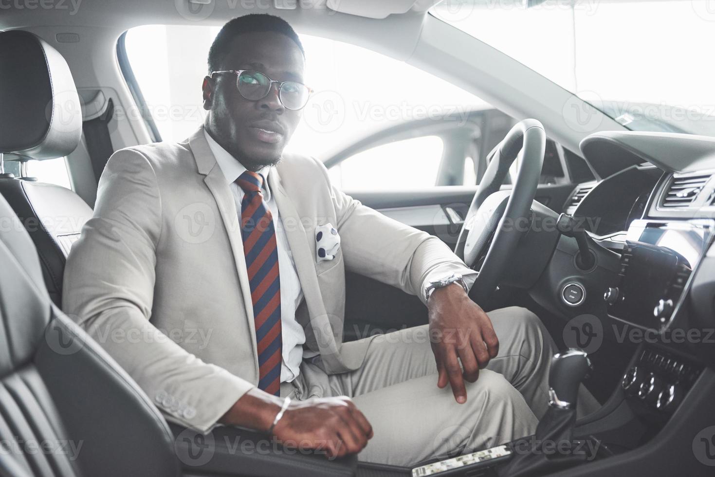 elegante empresário negro sentado ao volante de um carro de luxo. homem afro-americano rico foto