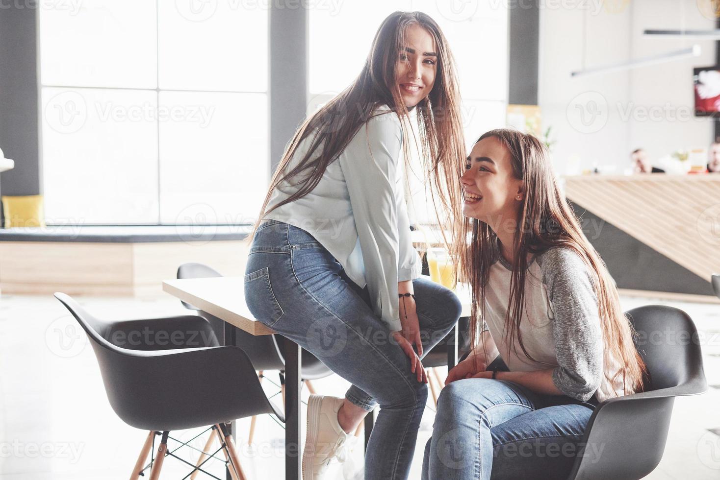 duas lindas gêmeas passam o tempo. irmãs relaxando em um café e se divertindo juntas e sussurrando foto