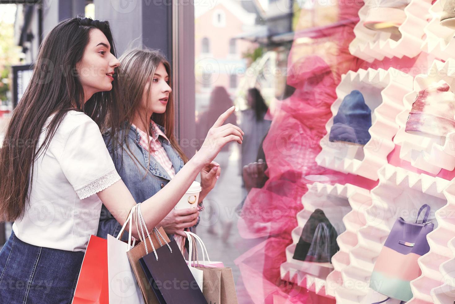 mulher feliz com sacolas de compras apontando o dedo na vitrine foto