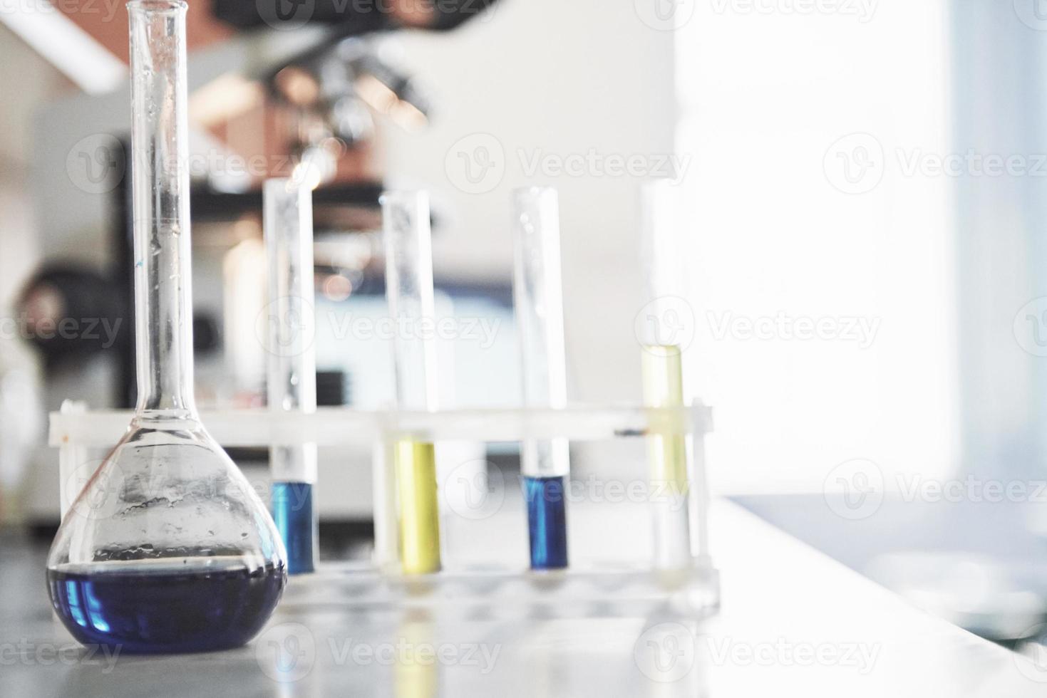 frasco com suporte de cortiça de laboratório com líquido azul púrpura rosa rosa sobre a mesa no teste de fluido de laboratório de teste foto