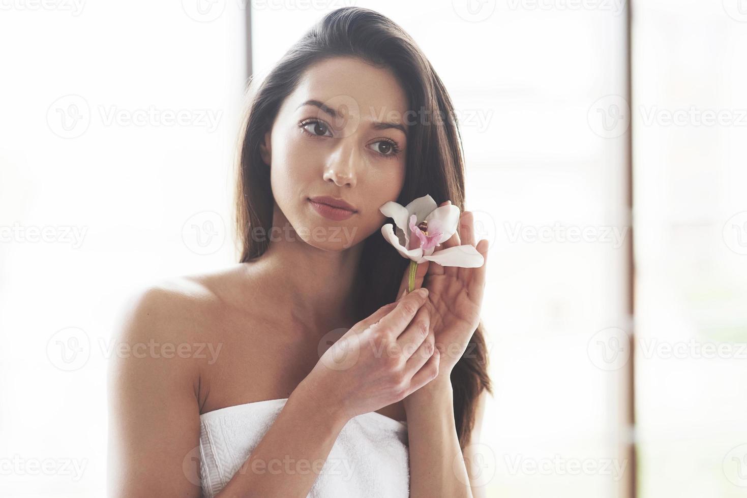 mulher jovem e bonita posando com orquídea. tratamento de cuidados da pele. foto