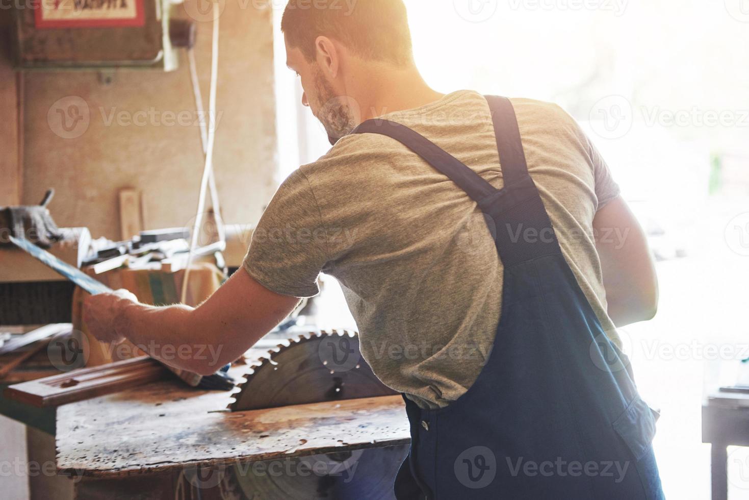 um homem trabalha em uma marcenaria, trabalhando com uma árvore. foto