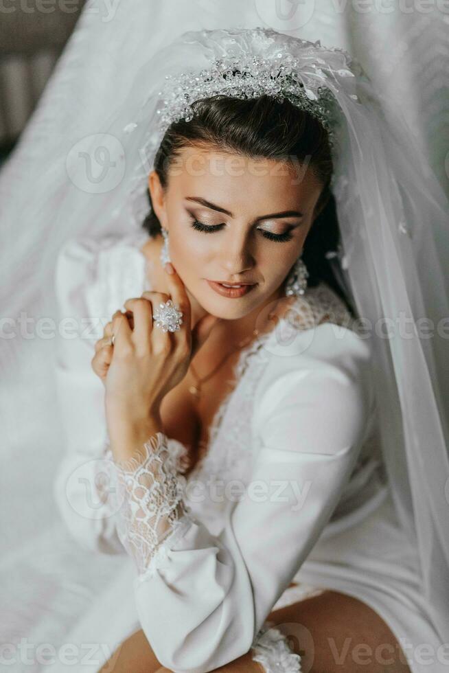 detalhes. Casamento acessórios. a morena noiva é vestindo uma anágua, segurando cristal brincos dentro dela mãos. volumoso véu. lindo mãos. aberto fracasso foto