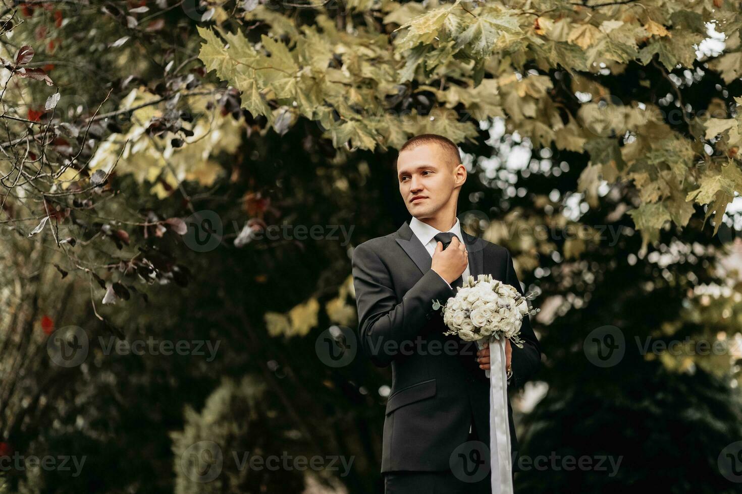 foto do a noivo dentro uma clássico Preto terno com uma ramalhete do flores dentro dele mãos