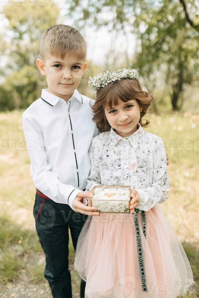 dois crianças, vestido festivamente, presente Casamento argolas para noivas foto