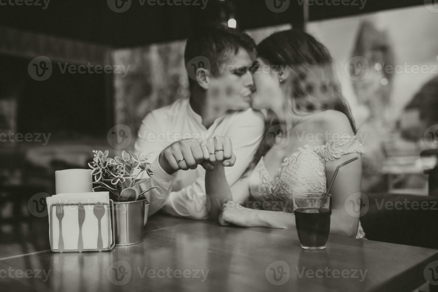 lado Visão retrato do uma amoroso europeu casal rindo enquanto desfrutando uma encontro dentro uma cafeteria. Preto e branco foto