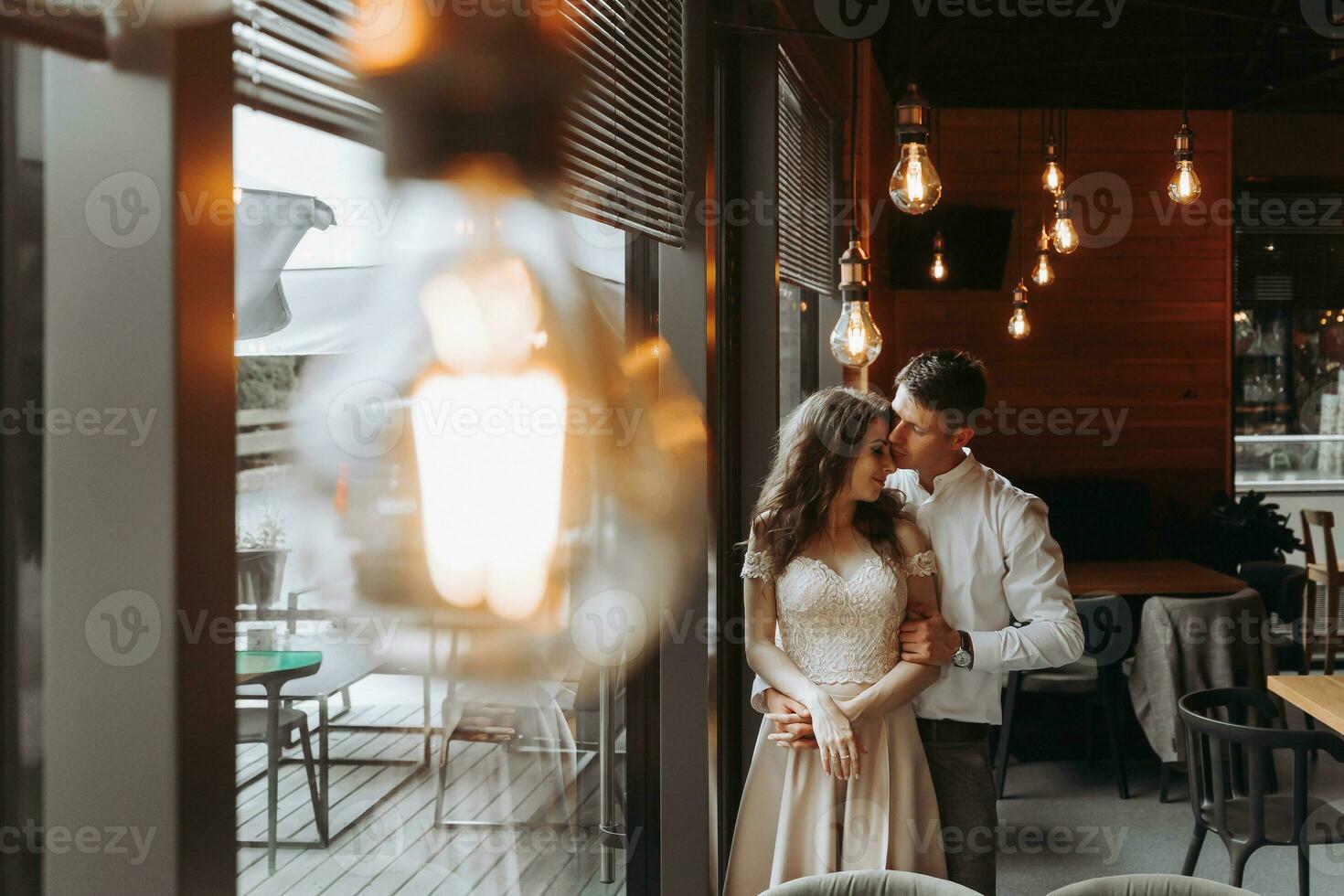 lado Visão retrato do uma rindo europeu casal desfrutando uma encontro dentro uma cafeteria com suspensão retro lâmpadas foto