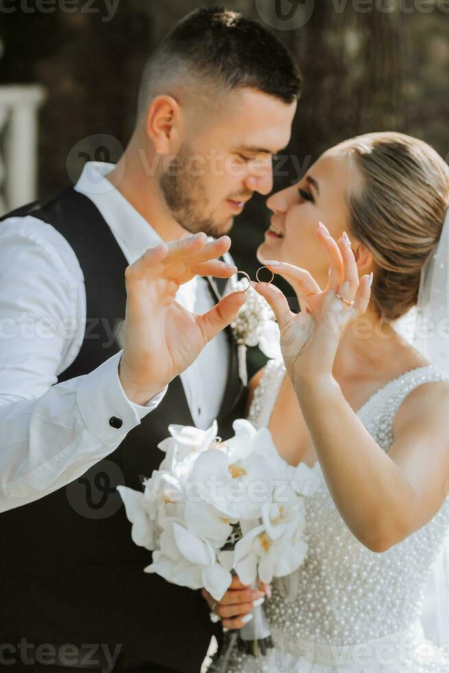jovem lindo Casamento casal romanticamente abraçando e desfrutando seus Casamento dia segurando Casamento argolas em seus dedos foto