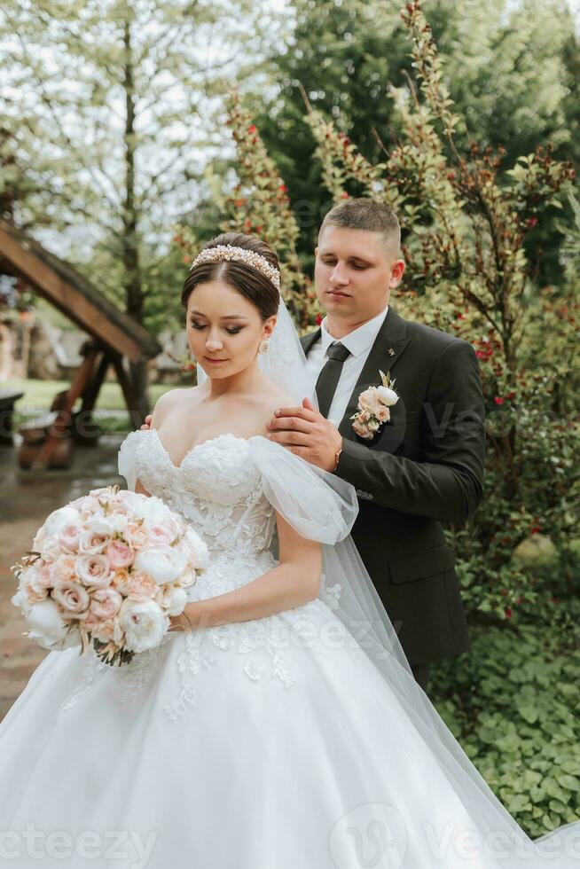 noivo e noiva se beijando dentro a parque. uma casal do recém-casados, a noiva e noivo, às uma Casamento dentro natureza, uma verde floresta, se beijando, foto retrato. Casamento casal