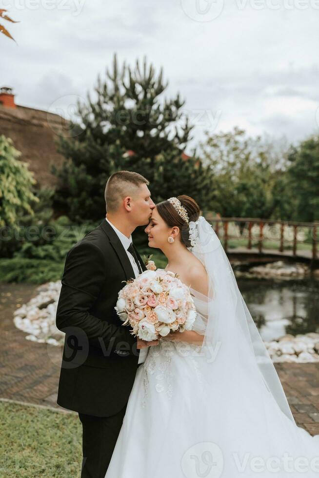 noivo e noiva se beijando dentro a parque. uma casal do recém-casados, a noiva e noivo, às uma Casamento dentro natureza, uma verde floresta, se beijando, foto retrato. Casamento casal