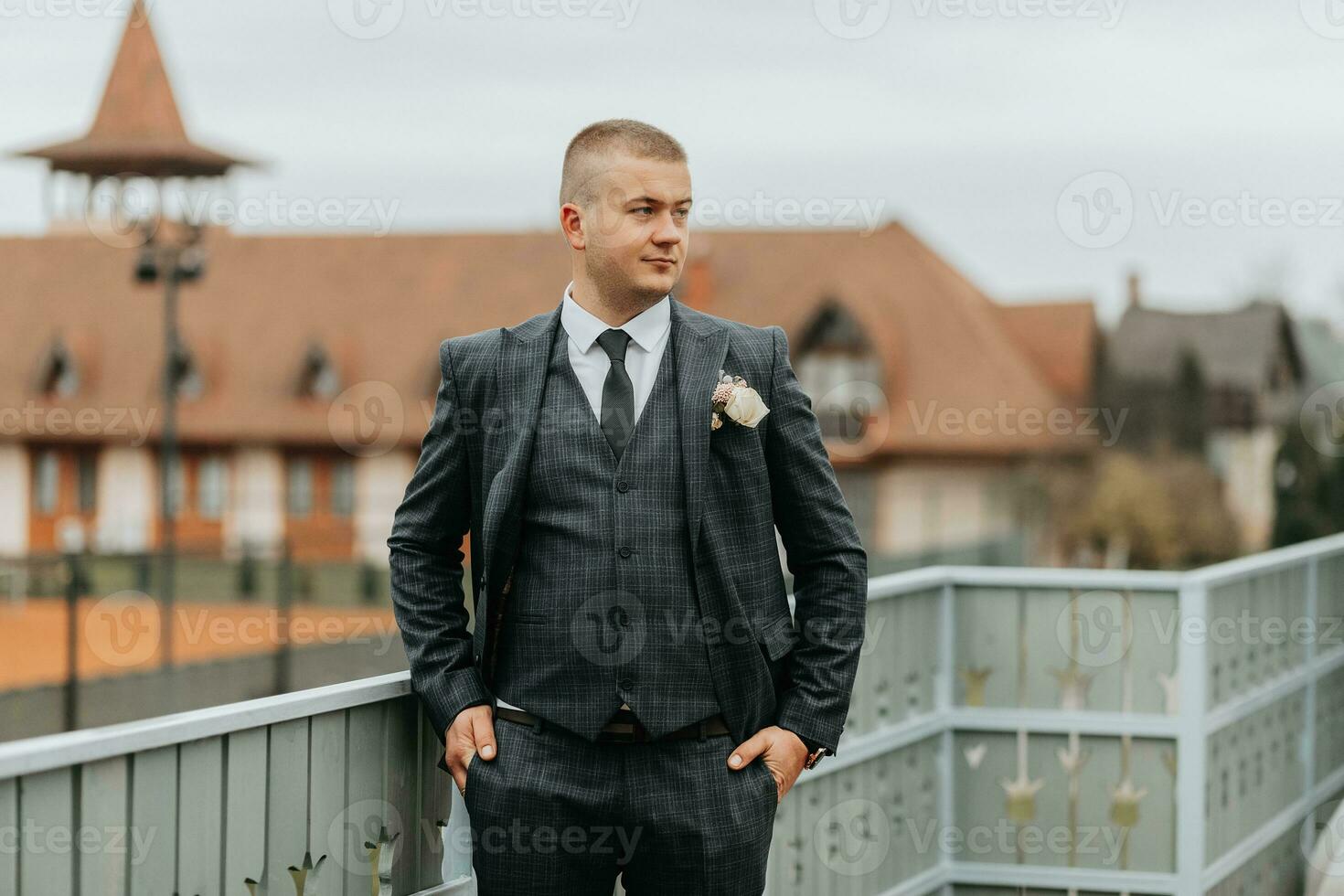 bonito noivo dentro terno e gravata em pé em sacada ao ar livre. Casamento retrato. uma homem dentro uma clássico terno foto