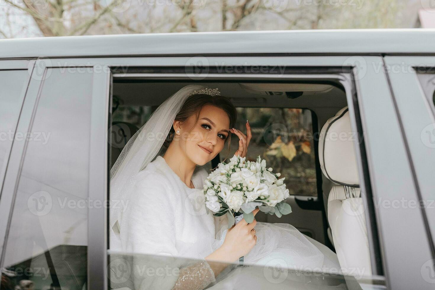 uma lindo sorridente noiva em dela Casamento dia é sentado dentro uma carro e segurando uma Casamento ramalhete do branco e Rosa rosas. uma jovem mulher com uma lindo Penteado regozija-se em dela Casamento dia foto