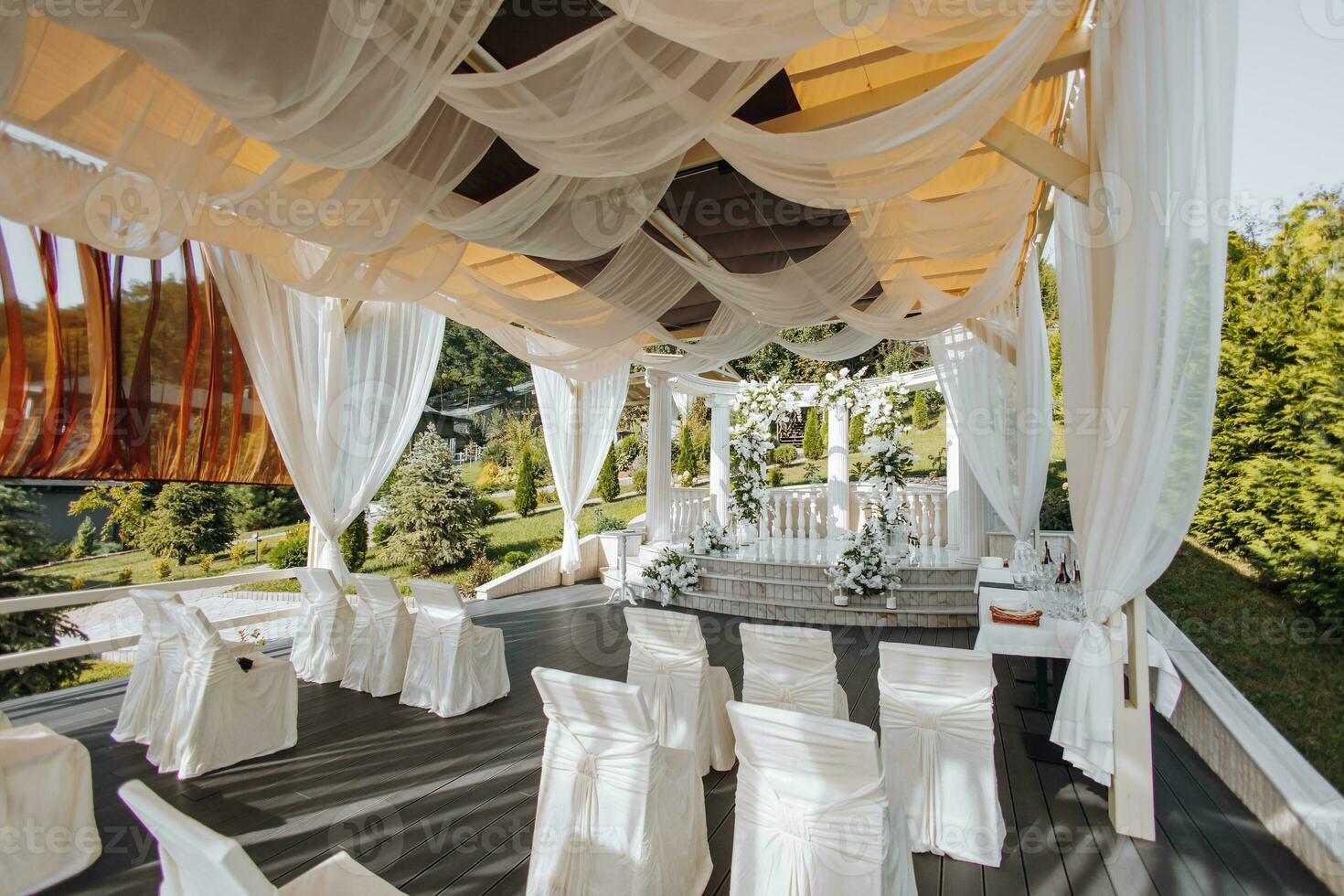 a Casamento cerimônia é decorado com fresco flores em a localização com alta branco colunas. preparação para a Casamento cerimônia foto