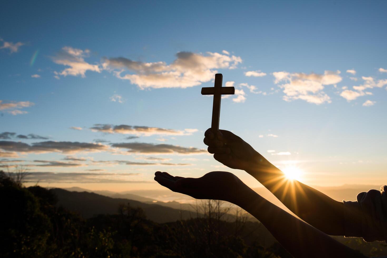 silhueta da mão segurando a cruz de Deus foto