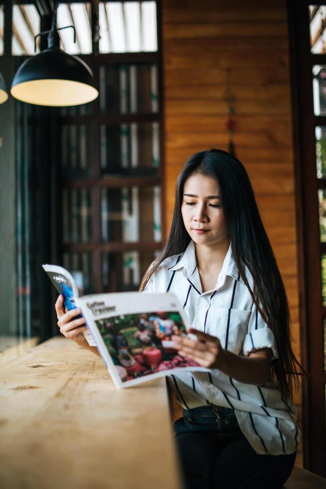 linda mulher lendo revista no café foto