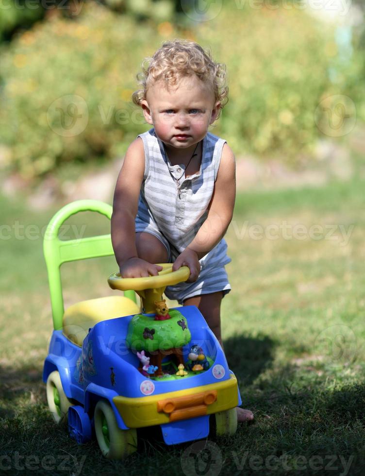 lindo menino com carrinho de brinquedo infantil posando fotógrafo foto