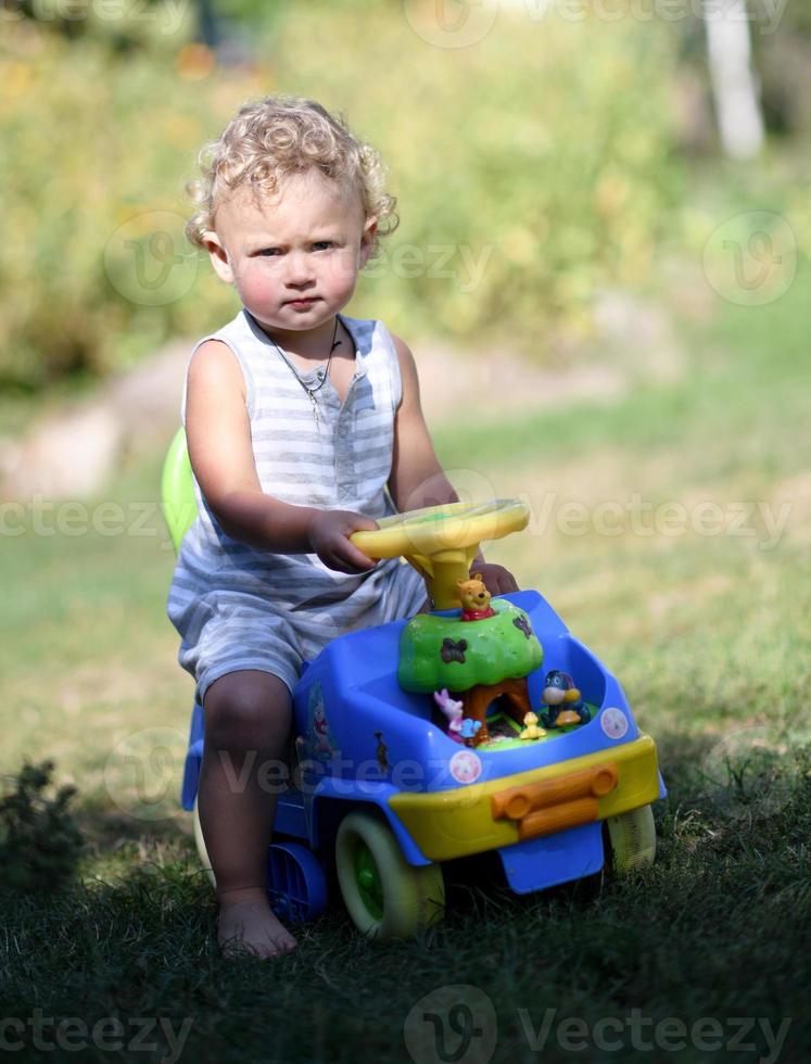 lindo menino com carrinho de brinquedo infantil posando fotógrafo foto