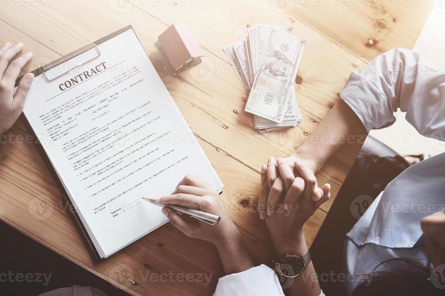 o cliente segura uma caneta e lê as condições para assinar com o vendedor o contrato de compra e venda de seguro residencial. foto