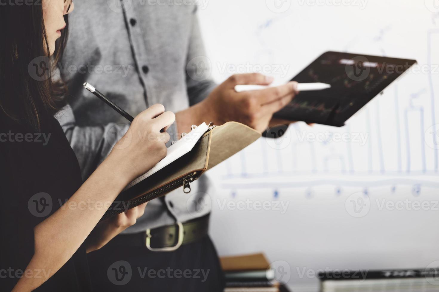 mulher usando caneta para anotações com um especialista em investimentos aponta uma caneta para um monitor de tablet para analisar o mercado de ações e ensiná-lo a ter lucro. foto