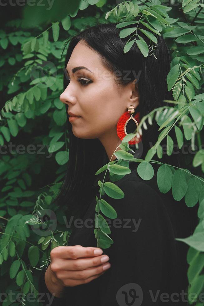mulher de vestido preto e enfeites vermelhos no fundo da floresta foto