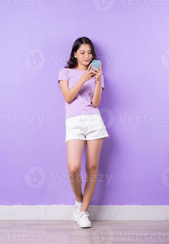 imagem de corpo inteiro de uma jovem asiática em fundo roxo foto