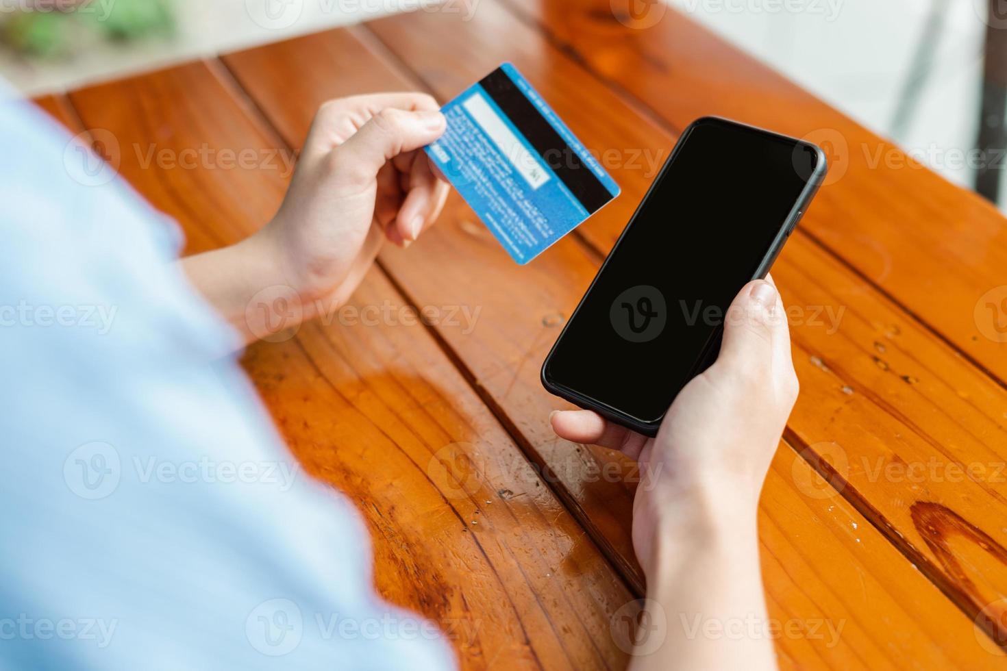 mão de uma mulher segurando um cartão de pagamento e usando o smartphone foto