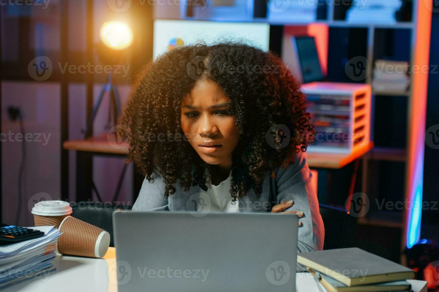 o negócio mulher bebendo café para pegue alguns energia para trabalhando hora extra sentado às escrivaninha usando computador e fazendo hora extra foto