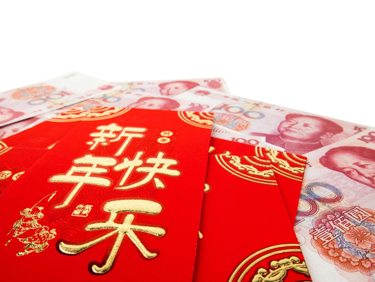 envelopes vermelhos chineses sobre dinheiro chinês pilha de notas de cem yuans, isolada no fundo branco. texto chinês no envelope significa feliz ano novo chinês foto