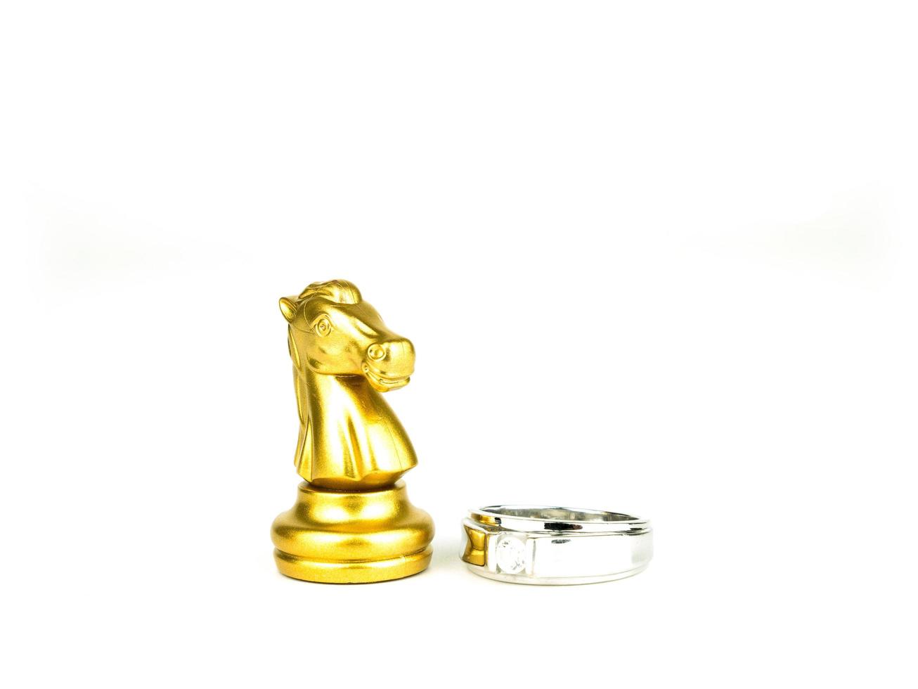 anel de diamante com xadrez de cavalo dourado isolado no fundo branco, conceito de casamento foto