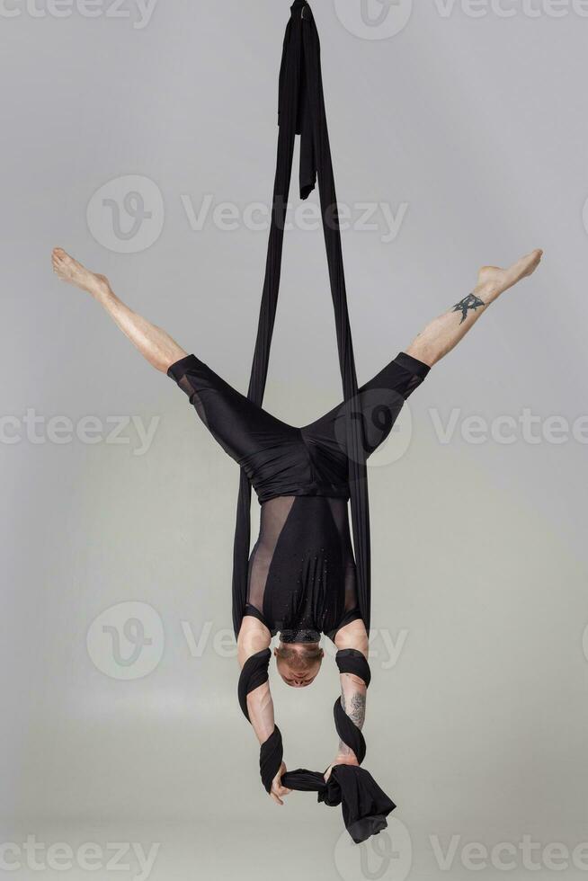 Atlético homem dentro uma Preto esporte terno é realizando a acrobático elementos dentro uma estúdio. foto