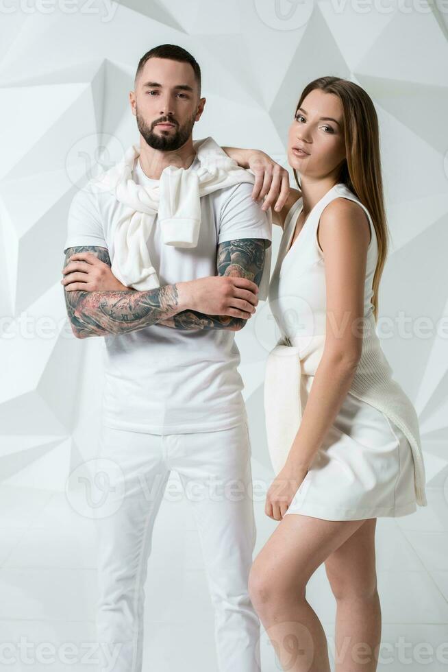 casual casal perto uma branco parede, homem e mulher dentro branco roupas. foto