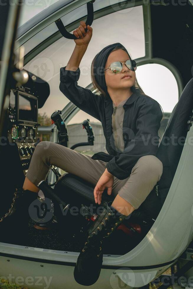 interpolação menina dentro espelhado oculos de sol sentado em pilotos assento dentro aberto helicóptero foto