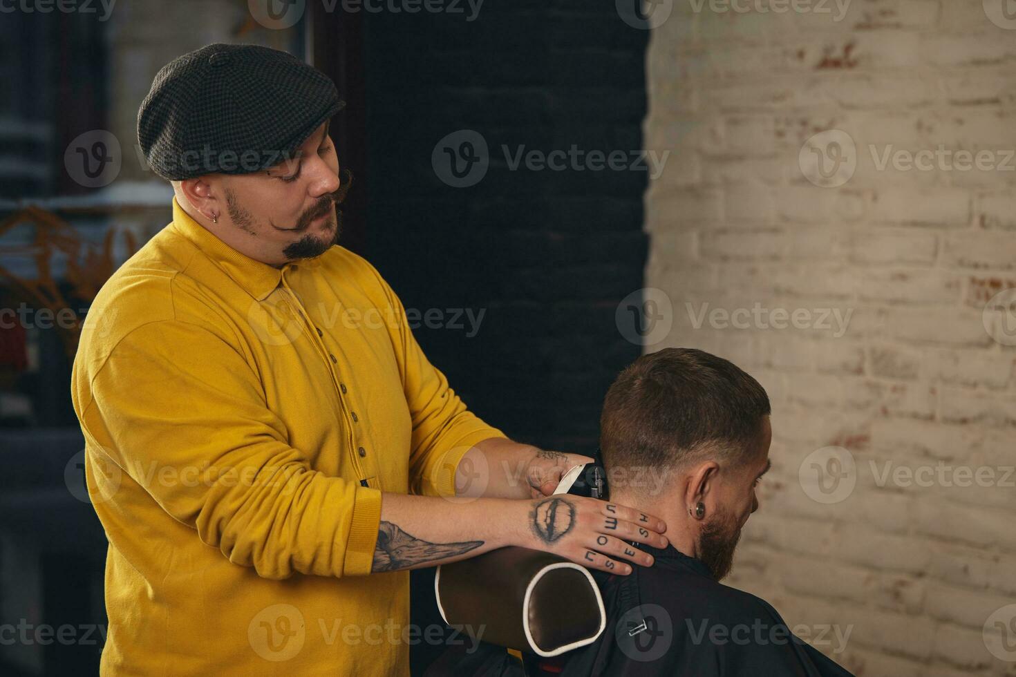 barbeiro fazendo corte de cabelo de atraente homem barbudo na barbearia foto