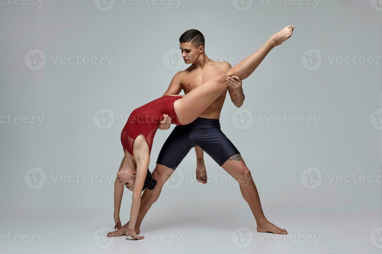 a casal do a Atlético moderno balé dançarinos estão posando contra uma cinzento estúdio fundo. foto