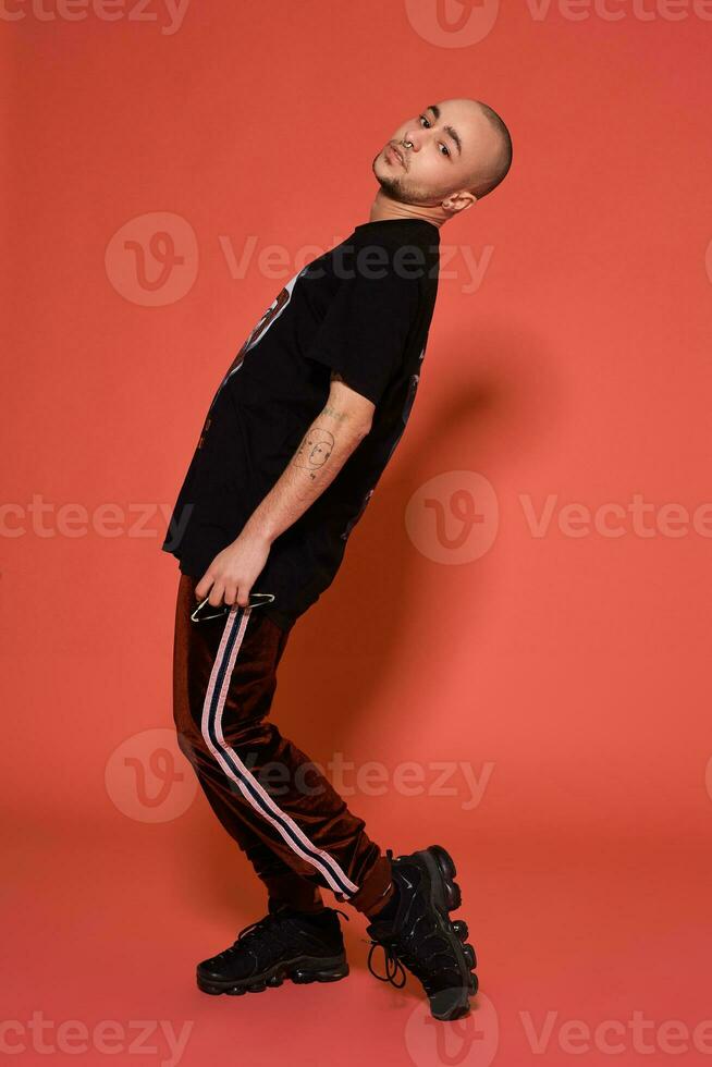 estúdio tiro do uma jovem tatuado Careca homem posando contra uma Rosa fundo. anos 90 estilo. foto