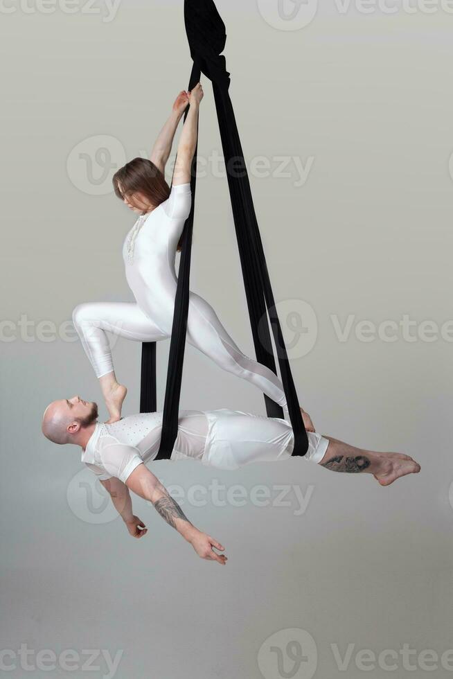 lindo menina e a Atlético homem dentro uma branco esporte ternos estão realizando a acrobático elementos dentro uma estúdio. foto