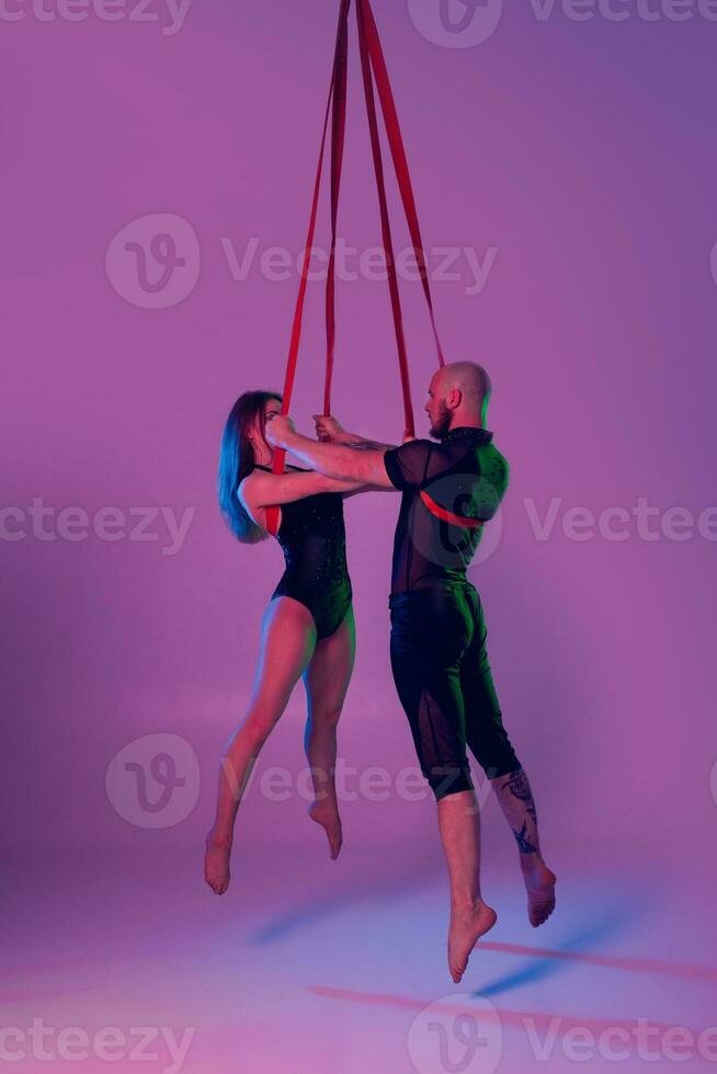 lindo menina e a Atlético homem dentro uma Preto esporte ternos estão realizando a acrobático elementos dentro uma estúdio. foto