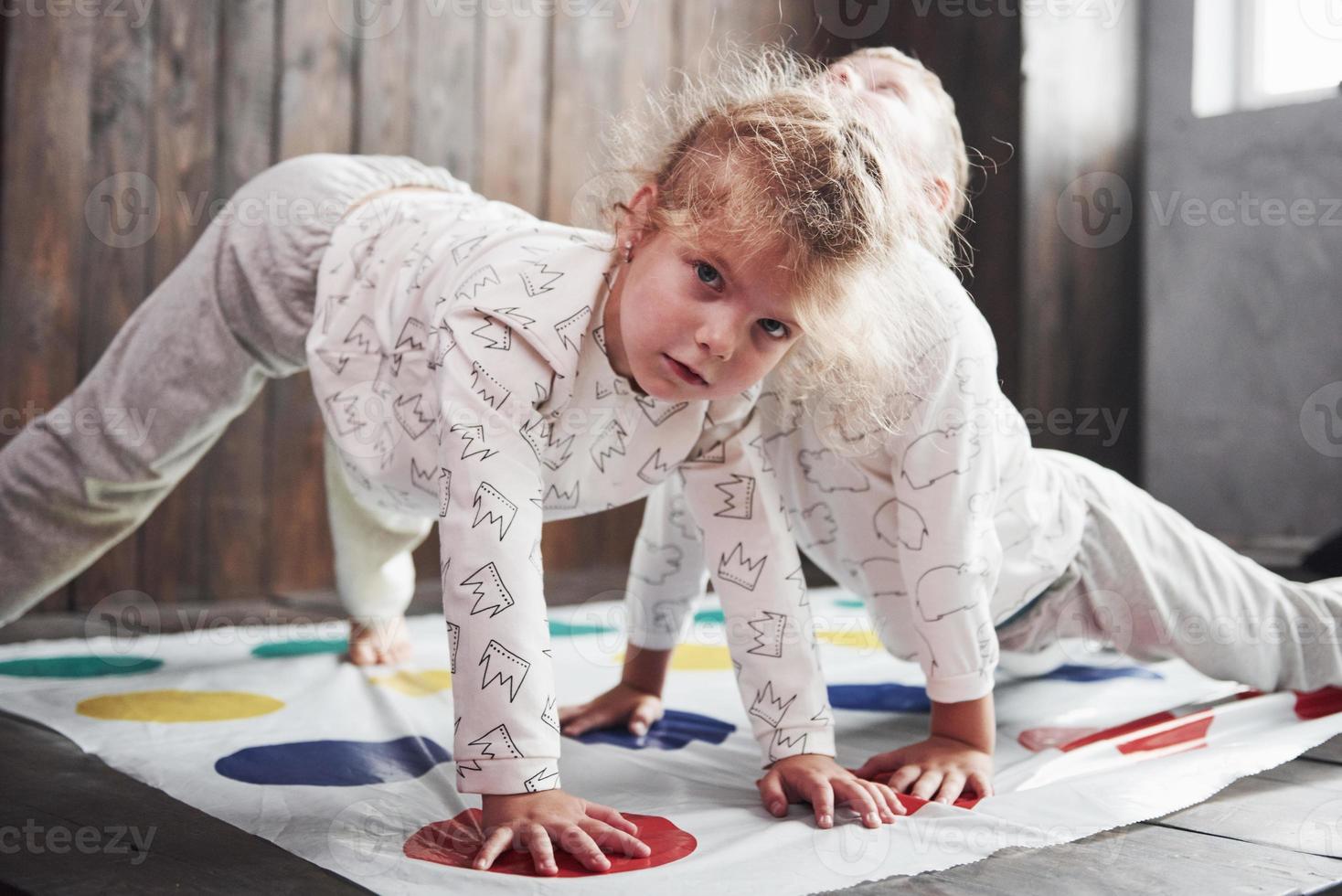 duas de crianças felizes brincando no twister em casa. irmão e irmã se divertem no feriado foto