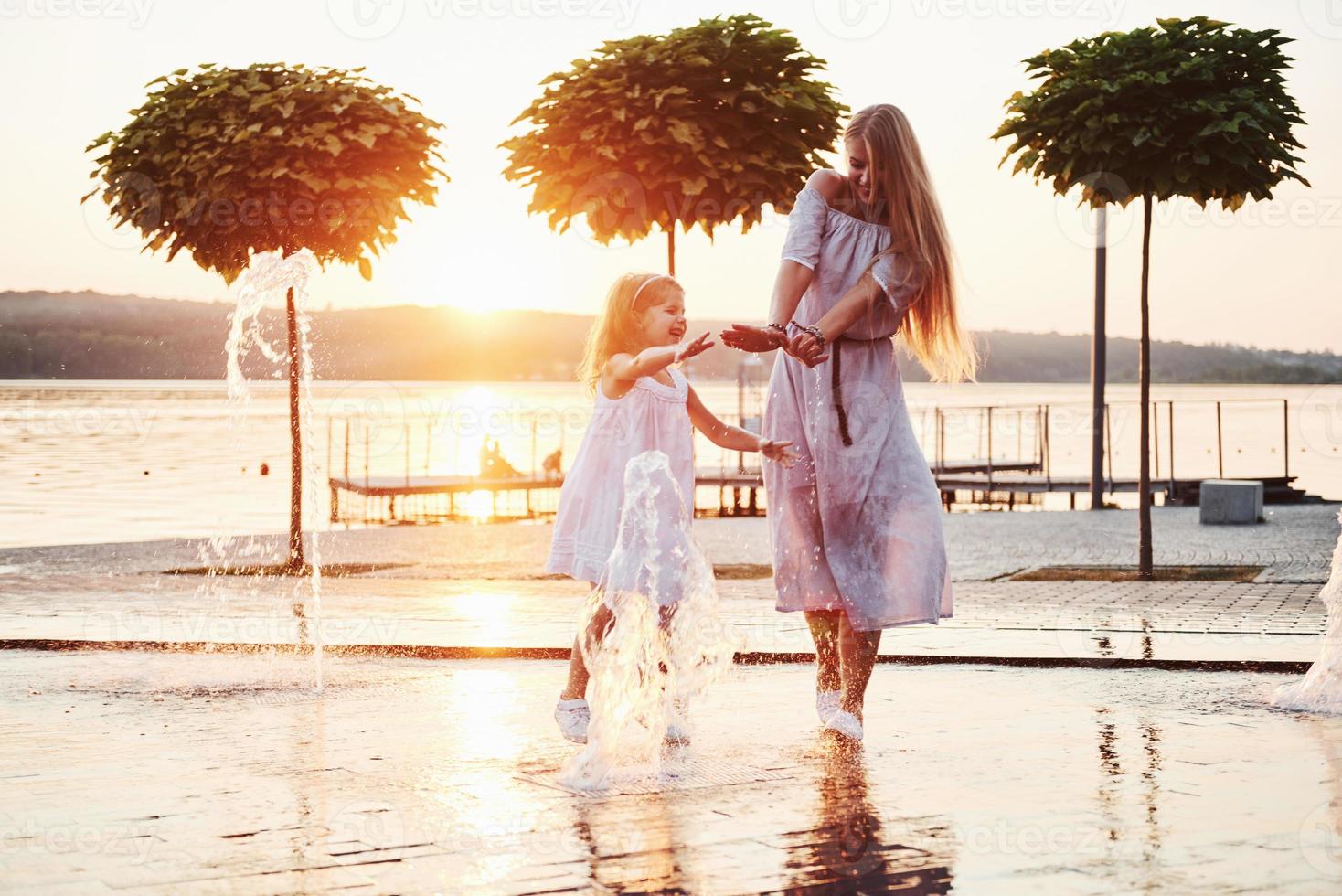 mãe com bebê perto da fonte ao pôr do sol foto