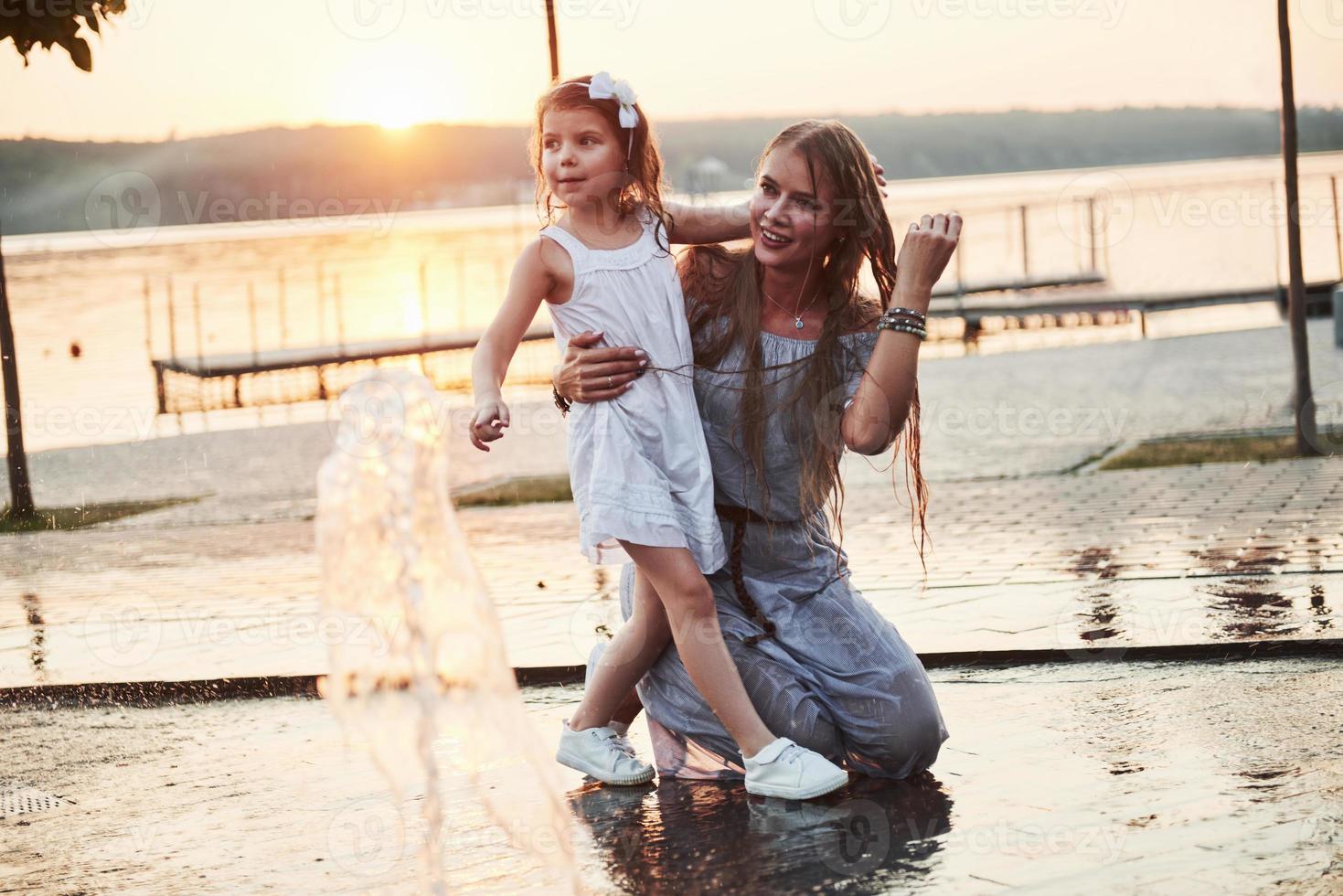 mãe com bebê perto da fonte ao pôr do sol foto