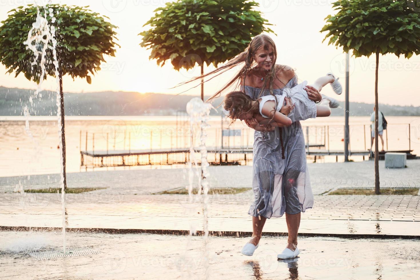 mãe com bebê perto da fonte ao pôr do sol foto